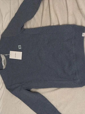 Blå sweatshirt från Les Deux XS - Snygg blå sweatshirt från Les Deux i storlek XS. Tröjan har ett stilrent broderat II-märke på bröstet och är tillverkad i mjuk bomull. Rund hals och ribbade muddar vid ärmslut och nederkant. Perfekt för chill dagar och enkel att matcha.
