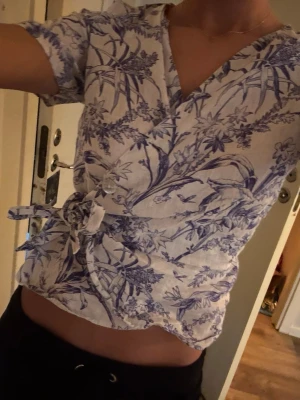 Blå blommig omlott topp  - Supersöt kortärmad omlott topp ifrån H&M💐 Storlek M 🙌 Blå och vit med blommor!