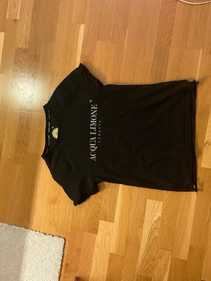 Svart Acqua Limone t-shirt - Säljer en svart t-shirt från Acqua Limone i storlek M. T-shirten har ett stort citrontryck i gult på ryggen och logga på bröstet. Klassisk rund hals och korta ärmar. Materialet är mjuk bomull som känns skön mot huden. Perfekt för dig som gillar streetwear och tydliga prints.