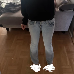 Ljusblå bootcut jeans med fickdetaljer - Säljer ett par ljusblå jeans med bootcut passform och snygga fickdetaljer bak med knappar. Jeansen har låg midja och klassisk femficksdesign. Storlek 36. Är 164cm och dom är bra i längden. Köptes i vintras för 500kr. Midjemått är 38/39cm 