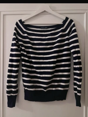 Randig offshoulder tröja  - Säljer en snygg marinblå och vit randig tröja   . Tröjan har offshoulder-design, långa ärmar och bred ribbad mudd vid ärmslut och nederkant. Perfekt för dig som gillar avslappnad och trendig stil.