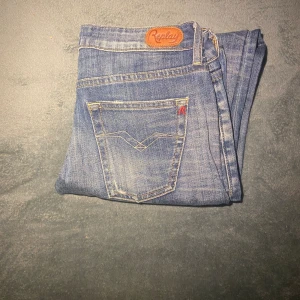 Blå Replay jeans bootcut 28/32 - Snygga blå jeans från Replay med bootcut passform och klassisk femficksdesign. Jeansen har slitningar och kontrastsömmar, samt Replay-logga på bakfickan och läderpatch i midjan. Tillverkade i 98% bomull och 2% elastan för skön stretch.