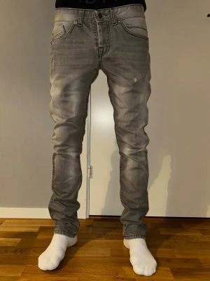 Grå jeans slim - Snygga grå jeans från Zana med unika detaljer på bakfickorna och en tvättad look. Jeansen har normal passform och slim ben, klassisk femficksmodell och knappgylf. Perfekta för dig som vill ha en cool och modern stil.32/32