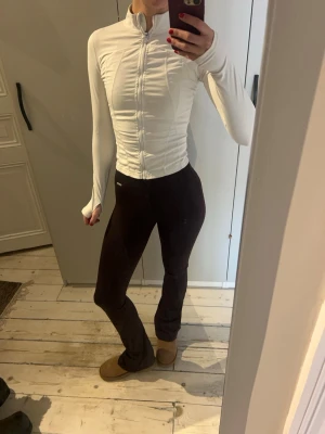 Träningsjacka - Säljer ett par bruna manchesterbyxor med bootcut passform. Byxorna är högmidjade och har en tight passning upptill som släpper ut vid bensluten. Materialet är mjukt och stretchigt, perfekt för en chill och snygg look.