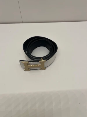Bälte - Ett vit bälte med guldigt H. Den är helt ny och är 105 cm lång. Pris kan diskuteras och skriv om du har några frågor. 