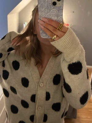 Beige kofta med svarta prickar, Kappahl  - Säljer en beige kofta från kapphal med svarta prickar. Koftan har v-ringning, ribbade muddar och knäpps med knappar framtill. Oversized passform och är perfekt för dig som gillar statement-plagg!