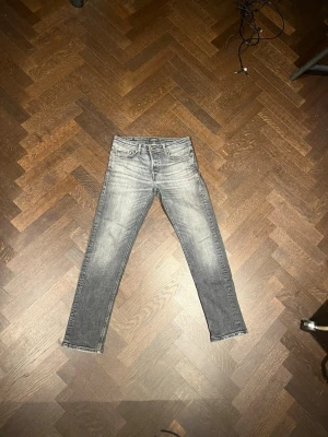 Grå slim straight jeans från jack and jones - Snygga grå jeans från jack and jones med slitna detaljer. Jeansen har en rak slim passform. Passar 170 cm långa