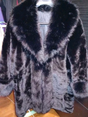 Svart pälsjacka med bred krage - Snygg svart pälsjacka med bred, fluffig krage och muddar. Jackan har en klassisk rak passform och är perfekt för att höja din outfit. Pälsen ger en lyxig känsla och jackan är enkel att matcha med olika stilar.