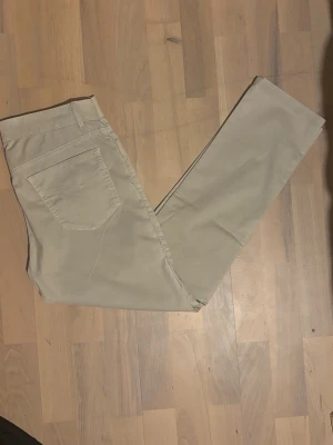 Beige chinos med raka ben - Snygga beige chinos med klassisk femficksdesign och raka ben. Det finns lite trådragningar samt två små ihopsydda hål som inte syns. Det är storlek 48 men den är lite mindre i storlek. Perfekt för sommaren 