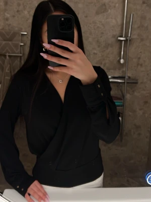 Omlott blus - Svart omlott blus köpt ifrån h&m, använd men fortfarande i fint skick! Den har guldknappar vid ärmarnas slut och sitter lite tajtare vid midjan. Storlek xs köpt för 299, hör av dig ifall du vill ha fler bilder eller funderar på något 