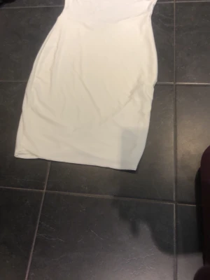 Vit kort klänning med snörning - Säljer en stilren vit kort klänning med snörningsdetaljer i sidan. Klänningen har en enkel, figurnära passform och är tillverkad i ett mjukt, stretchigt material. Perfekt för dig som gillar minimalistisk stil.Den har en fläck. Den är vid innersidan men den kommer inte att synas.