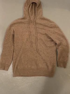 Brun Beige kashmirhoodie - Kashmirhoodie från NK i L. Skulle dock passa både M L och XL då kashmirer anpassar sig lite. Nypris ca 2000kr.