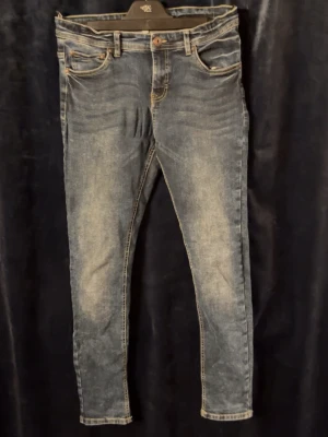 Blå Lab jeans med slitningar - Snygga blå Lab jeans med lätt slitna detaljer och klassisk femficksdesign. Jeansen har normal midja och perfekta till en avslappnad stil. Tillverkade i mjukt denimtyg för skön känsla hela dagen.