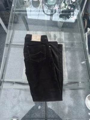 Jacob Cohen manchesterbyxor – brun – strl 33/33 - Snygga manchesterbyxor från Jacob Cohen i mörkbrun färg. Riktigt bra kvalitet med mjukt corduroy-tyg och clean passform. Funkar perfekt till både vardag och mer dressad stil.  Storlek 33/33. Klassisk 5-ficksmodell med Jacob Cohen-patch baktill. Made in Italy 🇮🇹 Skick: bra begagnat skick, normalt slitage men inga defekter.  Perfekt om du gillar premium plagg, stilrena byxor och tidlös design. Enkla att matcha med hoodie, stickat eller skjorta. 