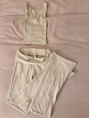 Loungewear-set från SKIMS - Säljer ett ljusgrönt loungewear-set från SKIMS med ribbat linne och matchande vida byxor med låg midja och bred linning. Storlek xxs i linnet och xs i byxorna.