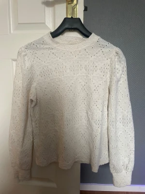 Vit spetsmönstrad tröja Holly & Whyte - Säljer en vit långärmad tröja från Holly & Whyte by Lindex i storlek XS. Tröjan har ett vackert spetsmönster och rund halsringning. 