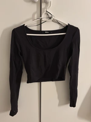 Svart croppad topp - Basic svart croppad topp från Bik Bok med lång ärm och rundad urringning, i storlek S. Stretchigt material. Lite skrynklig i bilden, den behöver bata strykas. Jättefin för vardagliga användningar. Gåva vid köp!🎁