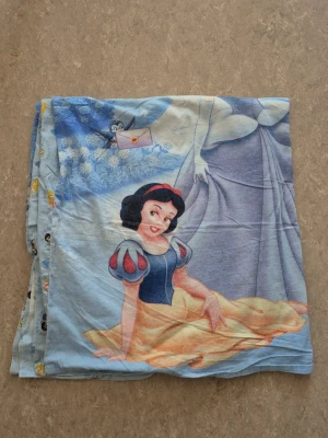 Påslakan - Säljer ett ljusblått påslakan med motiv av Snövit, Askungen och Aurora från Disney. Påslakanet har stora tryck på ena sidan och små prinsessmotiv med hjärtan på andra sidan. Mjukt material i bomull, perfekt för dig som älskar klassiska Disneyprinsessor.
