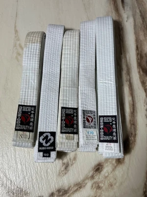 Vita Budo-Nord bälten i olika storlekar - Flera vita bälten från Budo-Nord, perfekta för kampsport som karate eller judo. Bältena är tillverkade i en mix av bomull och polyester och har klassisk design med broderad logotyp och japansk text. Finns i storlekarna 140, 150, 170 och 180 cm.