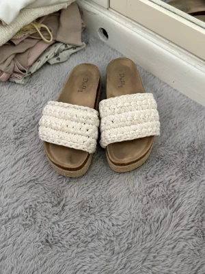 Vita flätade sandaler - Säljer ett par snygga sandaler från Duffy i storlek 39. De har en bred, flätad rem i vitt. Perfekta för sommaren och ger en chill vibe till alla outfits. De har en lite hög sula som jag tycker är väldigt snyggt! De är inte använda mycket alls!