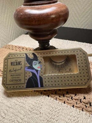 Disney Villains Maleficent lösögonfransar - Snygga lösögonfransar från Catrice i Disney Villains Maleficent edition. Fransarna är svarta, täta och ger en dramatisk look. Förpackningen är dekorerad med Maleficent och texten 'I Run This Castle'. Lim medföljer.