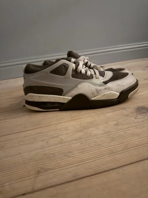 Nike Air Jordan 4 i grå och vit - Säljer ett par Nike Air Jordan 4 sneakers i grått och vitt med snygga detaljer. Skorna har snörning, mesh och mockaliknande partier samt en klassisk platt sula. Perfekta för dig som gillar streetwear och vill ha något stilrent men ändå sportigt.