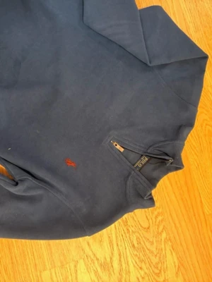 Blå half zip tröja från Polo Ralph Lauren - Säljer en marinblå långärmad tröja från Polo Ralph Lauren med röd broderad logga på bröstet. Tröjan  är liten i stolek är INTE ÄKTA, står M men passar bra för xs