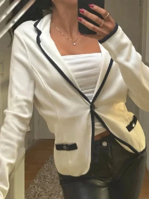 Vit kavaj med svarta detaljer - Stockh LM - Snygg vit kavaj med svarta kanter och svarta detaljer vid fickorna. Jackan har en knapp framtill och är figursydd med lång ärm. Perfekt för dig som vill ha en stilren och modern look. Passar till både jeans och kostymbyxor.