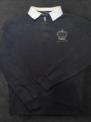 Gant långärmad pikétröja- strl L - Säljer en svart GANT långärmad pikétröja i storlek L  👕 Märke: GANT 📏 Storlek: L 🎨 Färg: Svart 📍 Skick: Mycket bra begagnat skick (se bilder)  💬 Har du några frågor är det bara att höra av dig! 💰 Vid snabb affär kan priset diskuteras. 📦 Skickar alltid inom 24 timmar!