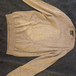 Beige stickad tröja från Oscar Jacobson  - En stilren beige stickad tröja från Oscar med rund halsringning och långa ärmar. Tröjan har en klassisk passform och ribbade muddar vid ärmslut och nederkant. Perfekt för lager-på-lager under kyliga dagar. Nypris 1200. Säljs då den är för liten. I toppskick använd max 3 gånger