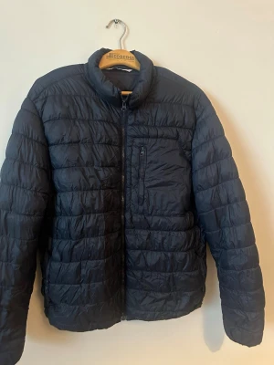 Svart pufferjacka från ZARA XXL - Säljer en svart pufferjacka från ZARA i storlek XXL. Jackan har quiltad design, hög krage och dragkedja framtill samt en bröstficka med dragkedja. Perfekt för kyliga dagar och enkel att matcha med olika outfits.