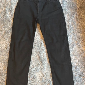 Svarta jeans från Grunt - Svarta jeans från Grunt med klassisk femficksdesign och raka ben. Jeansen har en stilren look med svart läderpatch bak i midjan. Tillverkade i ett mjukt bomullstyg med lite stretch för extra komfort. Perfekta för dig som gillar en enkel och clean stil.