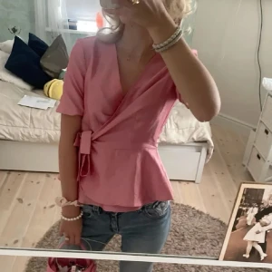 Rosa omlottopp - Säljer en superfin rosa omlottopp med korta ärmar och knyt i sidan. Storlek M men passar även S. 💞