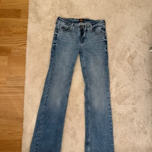 Ljusblå bootcut jeans från Lee - Snygga ljusblå jeans från Lee med klassisk femficksdesign och bootcut-ben. Jeansen har låg midja, Lee-lapp bak i brunt läder och är tillverkade i mjukt denimtyg. Ett par helt perfekt low waist bootcut😍😍storlek 25/31❤️knappt använda