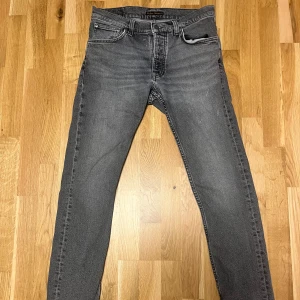Nudie Jeans Grim Tim - Säljer att par riktigt najs par Jeans i modellen Grim Tim. Färgen är grey day. Jeansen är mycket sparsamt använda men det förekommer enstaka fläckar på framsidan och en väldigt väldigt liten röd färgfläck på höger framsida. Bara att fråga ifall något undras!