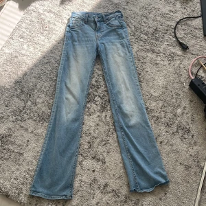Bootcut jeans från &Denim ljusblå - Bootcut jeans i ljusblå denim från &Denim. Modellen har låg midja och klassisk femficksdesign. Jeansen har en snygg tvätt med lätt slitning framtill och bakfickor. Perfekta för dig som gillar en avslappnad och trendig look.