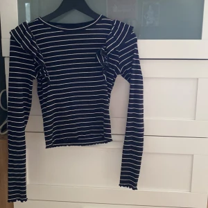 Randig volangtröja  från Kappahl - Svart och vit randig långärmad tröja från Kappahl. Modellen har volangdetaljer på axlarna och har en tight passform. Tillverkad i ribbad bomull som ger en skön stretchig känsla. Perfekt för dig som gillar en trendig och bekväm stil.säljer då den aldrig har kommit till andvändning och är för liten. skicka om ni har frågor 💗