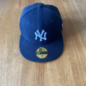 Mörkblå New Era Yankees keps - Säljer en mörkblå New Era 59FIFTY keps med New York Yankees-logga framtill. Klassisk rak skärm och broderade detaljer.  MLB-logga bak samt New Era-logga på sidan. Perfekt för dig som gillar streetwear och sportig stil.I princip helt ny inte använd så mycket. Buda gärna och hör av er vid minsta fundering!🙌🏽