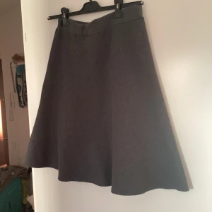 Grå kjol från Holly & Whyte - En stilren grå kjol från Holly & Whyte by Lindex i klassisk A-linjeform. Kjolen är enkel och tidlös, perfekt att matcha med både stickade tröjor och t-shirts. Mjuk och bekväm, passar dig som gillar minimalistisk stil.