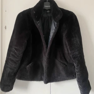 Svart pälsjacka från ONLY, stl S - Mysig svart pälsjacka från ONLY med klassisk krage och knäppning framtill. Jackan har en fluffig yta och är helfodrad på insidan, perfekt för kyliga dagar. Snygg och enkel att matcha med olika outfits.