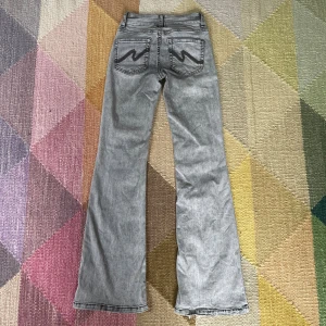 Grå bootcut jeans från Nelly - Grå jeans från Nelly med bootcut-ben och klassisk femficksdesign. Snygga svarta broderade detaljer. Jeansen har en rak passform upptill och är tillverkade i denim med en tvättad look. Jeansen är lite slita längst ner (se sista bilden) pris kan diskuteras 