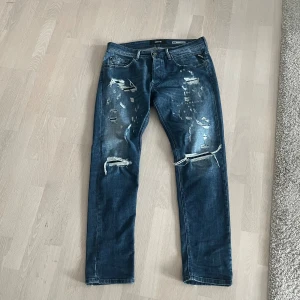 Replay jeans - Säljer ett par blå jeans från Replay, modell Willbi Broken Edge i regular slim fit. Jeansen har feta slitningar och i riktigt fint skick