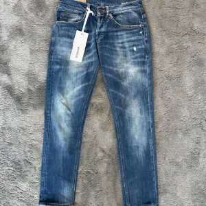 Dondup george, storlek 30 - Snygga blå jeans från Dondup med slitna detaljer. Klassisk femficksmodell med orange sömmar och diskret logga bak. Jeansen har rak passform och är tillverkade i mjukt bomullsjeans.