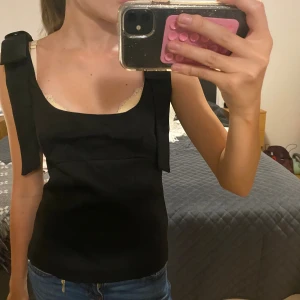 Svart topp med rosettband - Supersnygg svart Zara liknande topp i storlek xs men passar s 💗endast använd när bilden togs. Priset kan diskuteras! Vet ej märke💗