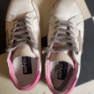 Golden Goose sneakers med rosa detaljer - Golden Goose sneakers i vitt skinn med grå mockastjärna på sidan och grå snörning. Bra skick. 