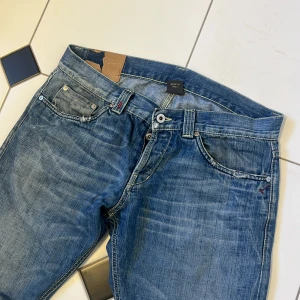 Blå jeans från Dondup med detaljer - Snygga blå jeans från Dondup med slitningar och coola detaljer på bakfickorna. Klassisk femficksmodell med kontrastsömmar och en avslappnad vibe. Perfekta för dig som gillar en streetig och trendig look.