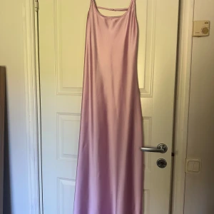 Ljusrosa långklänning i satin från Zara - Säljer en ljusrosa långklänning i satin med smala axelband och snyggt öppen rygg. Från Zara i storlek M. 