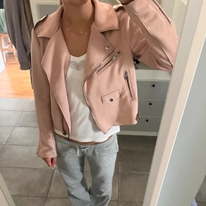 Ljusrosa mockajacka från ONLY, stl 38 - Säljer en ljusrosa mockajacka från ONLY i storlek 38. Jackan har dragkedjor, axelklaffar och snygga detaljer med knappar. Materialet känns mjukt och mockaliknande, perfekt som vår och sommar jacka