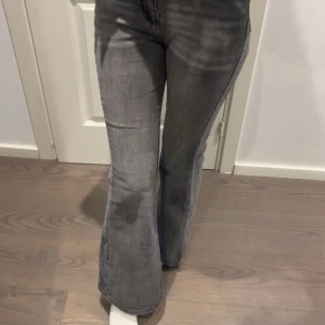 Grå bootcut jeans - Säljer ett par gråa jeans med bootcut-modell och mellan midja. Jeansen har klassisk femficksdesign och är i ett mjukt denimtyg med lite stretch. Snygg tvättad look som passar perfekt till sneakers eller boots.