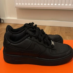 Nike Air Force 1 helsvarta sneakers - Klassiska Nike Air Force 1 svarta sneakers i storlek 37,5. Har använd några gånger bara. 